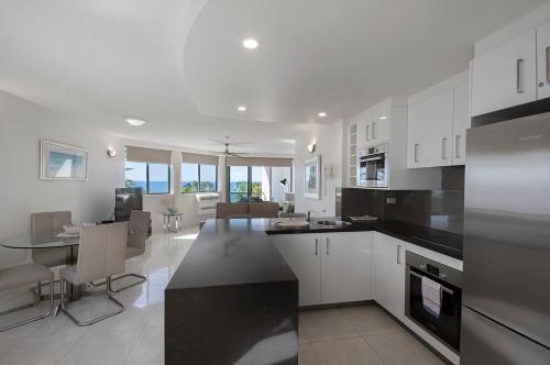 a kitchen and living room with white cabinets and a table at Malibu Apartments in Mooloolaba