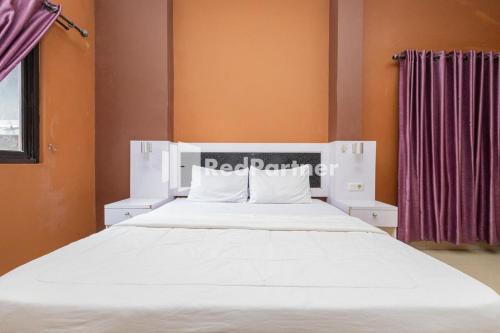 1 dormitorio con 1 cama blanca grande y paredes de color naranja en Star Hotel Jaksa Mitra RedDoorz en Yakarta