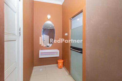 a bathroom with an orange wall and a mirror at Star Hotel Jaksa Mitra RedDoorz in Jakarta