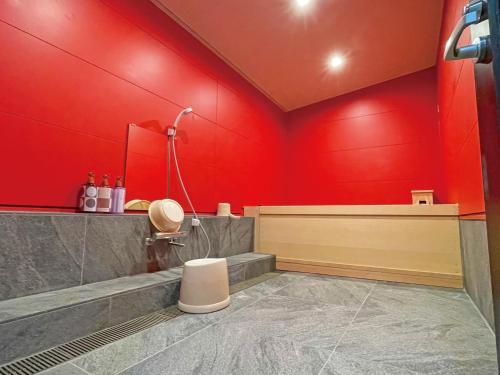 a bathroom with red walls and a shower and a toilet at 真田昌幸-幸村父子の隠れ宿 紀伊見荘 in Hashimoto