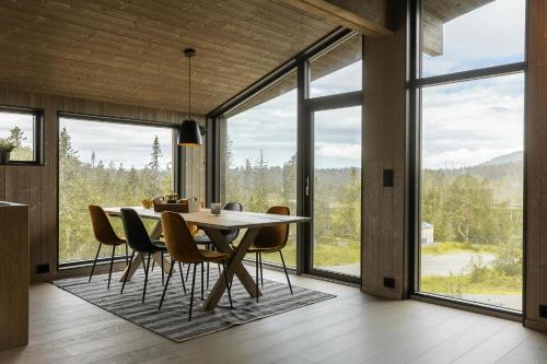 una sala da pranzo con tavolo, sedie e ampie finestre di Moderne hytte på Norefjell a Noresund