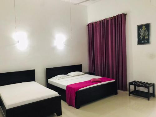 a bedroom with two beds and a purple curtain at Hambantota Rest House in Hambantota