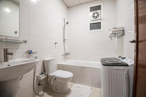 a white bathroom with a toilet and a sink at Ghalyt Ohud in Al Madinah