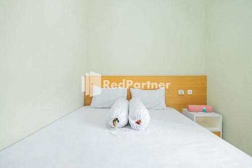 um quarto com uma cama branca e 2 almofadas em Atiq Homestay Syariah Mitra RedDoorz em Serang