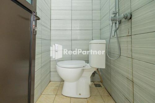 a white toilet in a bathroom with a shower at Atiq Homestay Syariah Mitra RedDoorz in Serang