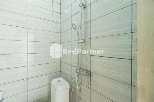 La salle de bains est pourvue d'une douche et de toilettes. dans l'établissement Atiq Homestay Syariah Mitra RedDoorz, à Serang