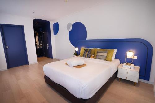 een slaapkamer met een groot bed met een blauw hoofdeinde bij Ukiyo Hotel in Petaling Jaya