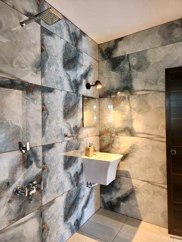 Un baño con lavabo y pared de mármol. en Native by Cliff and Coral, en Varkala