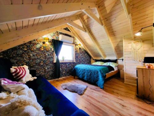 um quarto com um sofá e uma cama num sótão em Domki Lawendowy Zakątek em Boszkowo
