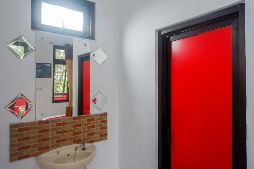 een badkamer met een rode deur en een wastafel bij RedDoorz near Alun Alun Wonosobo 2 in Wonosobo