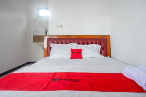 a bed with a red blanket on top of it at RedDoorz near Alun Alun Wonosobo 2 in Wonosobo