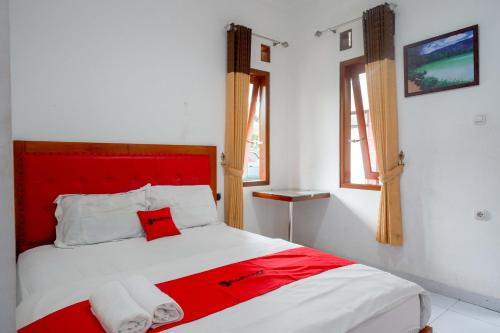 - un lit rouge et blanc dans une chambre blanche dans l'établissement RedDoorz near Alun Alun Wonosobo 2, à Wonosobo