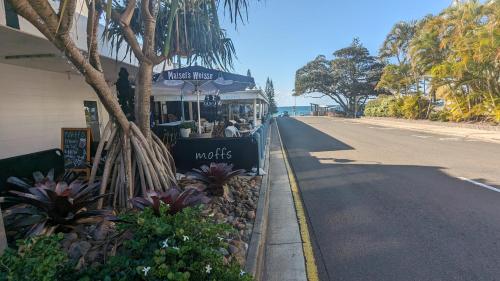 a store on the side of a street with flowers at Moffat Beach Motel Caloundra in Caloundra