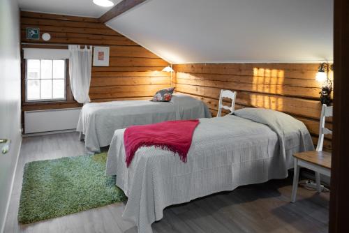 two beds in a room with wooden walls at Possakkatupa in Kuopio