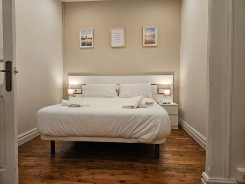 - une chambre avec un grand lit blanc et deux lampes dans l'établissement 135B2 Precioso Apartamento en Playa San Lorenzo, à Gijón