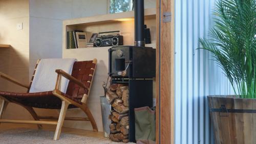 a room with a stove and a chair and a camera at Southern Highlands Vineyard Cabin by Outpost in Exeter