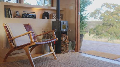 Habitación con silla y estufa de leña. en Southern Highlands Vineyard Cabin by Outpost, en Exeter