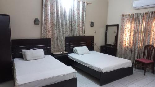 a bedroom with two beds and a mirror and a chair at Al Rehman guest hous in Hyderabad