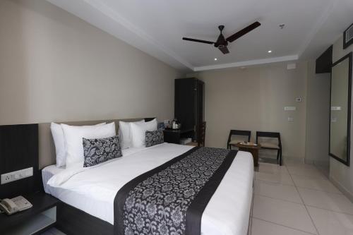 a bedroom with a large bed with a ceiling fan at Pride Biznotel Canopus, Digha in Digha