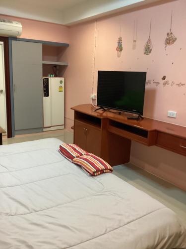 een slaapkamer met 2 bedden en een bureau met een televisie bij บ้านโนรีแมนชั่น in Si Racha