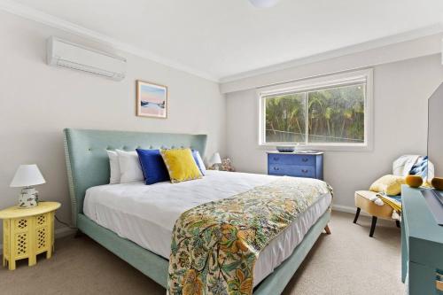 a bedroom with a bed and a window at Sunset Swirl - A Pastel Dream by the Beach in Sydney