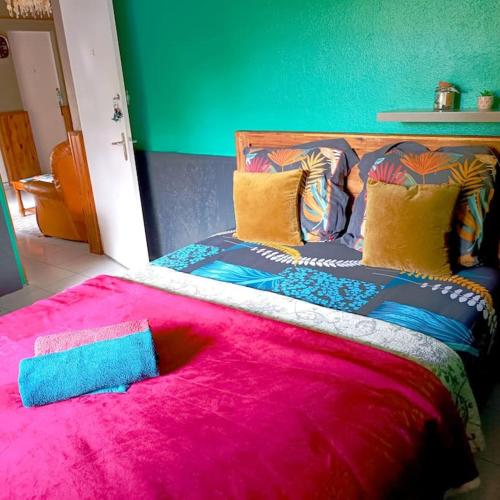 a bedroom with a large bed with a pink blanket at Chambre privée 2 - Case créole Le Mistral,chez Kévin in Saint-André