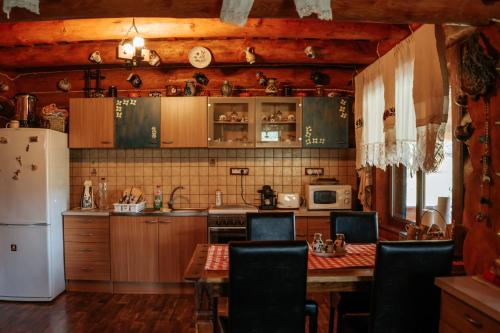 a kitchen with wooden cabinets and a table and a refrigerator at Casa din Busteni, Maramures in Hoteni