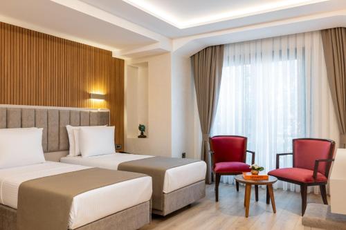 a hotel room with two beds and red chairs at Carina Gold Hotel in Istanbul
