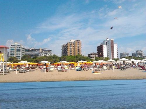a beach with chairs and umbrellas and people on it at Cristallo Sea View in Lignano Sabbiadoro