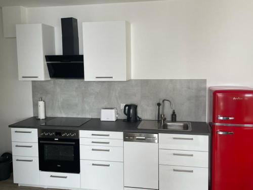 a kitchen with white cabinets and a red refrigerator at Logis Dutts in Neustadt an der Weinstraße
