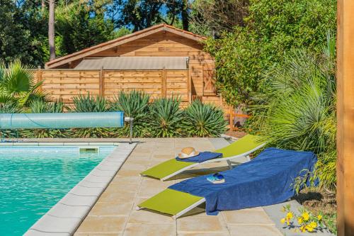 - une piscine avec 2 chaises longues à côté de la piscine dans l'établissement La maisonnette en bois, à Saumos