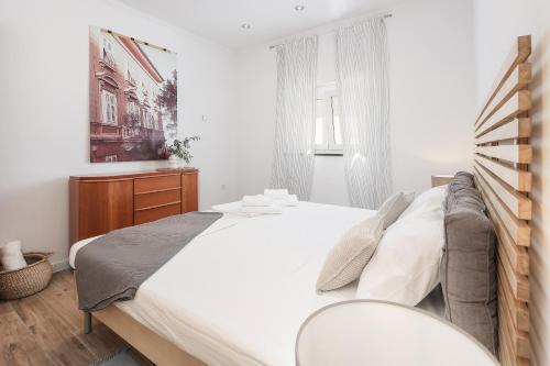 a white bedroom with a large bed and a window at Apartment FERIA 2 in Opatija
