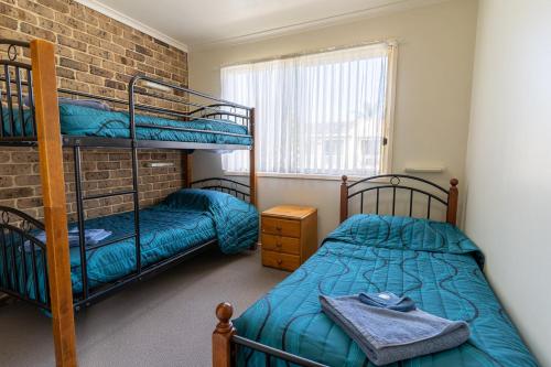 a bedroom with two bunk beds and a brick wall at Beachfront Apartments in Merimbula