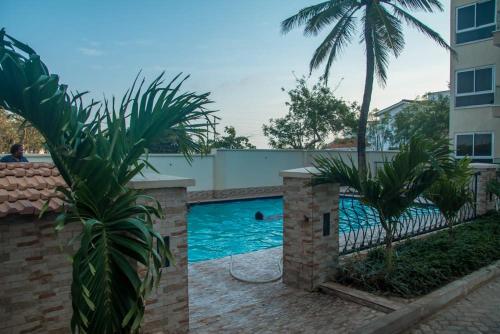 una piscina con una palmera y un edificio en Lux Suites Le Royal Apartments Nyali en Mombasa