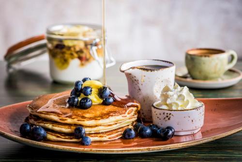 a plate of pancakes with syrup and blueberries and coffee at Marriott Executive Apartments Dubai Creek in Dubai