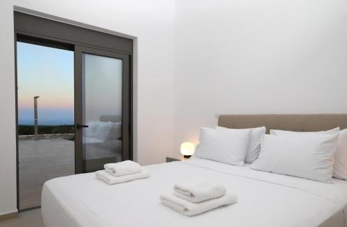 a bedroom with a white bed with towels on it at Villa Tropicana, luxury villa with pool by Sternes Properties in Sitia