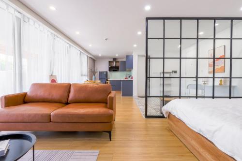 a bedroom with a bed and a brown leather couch at LAGOM APARTMENT AND HOTEL in Da Nang