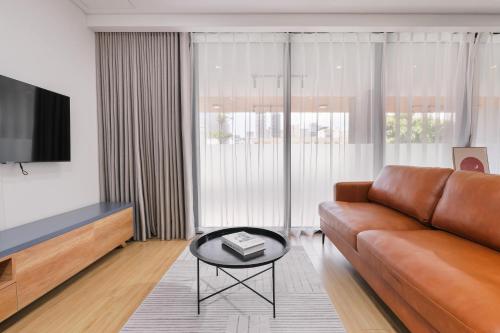 a living room with a brown leather couch and a table at LAGOM APARTMENT AND HOTEL in Da Nang