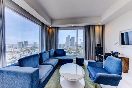 a living room with blue furniture and a large window at Cinnamon Red Colombo in Colombo