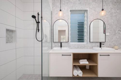 a bathroom with two sinks and a shower at Poolside Glamour - A Stylish Newcastle Hideaway in Newcastle
