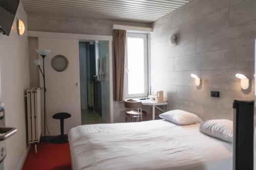 a bedroom with a bed and a desk and a window at Hotel Richmond in Blankenberge