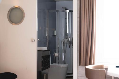 a bathroom with a shower with a toilet and a mirror at Hotel Richmond in Blankenberge