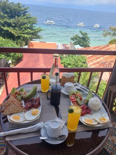 a table with breakfast food on a balcony with the ocean at Strandhaus Condotel in Moalboal