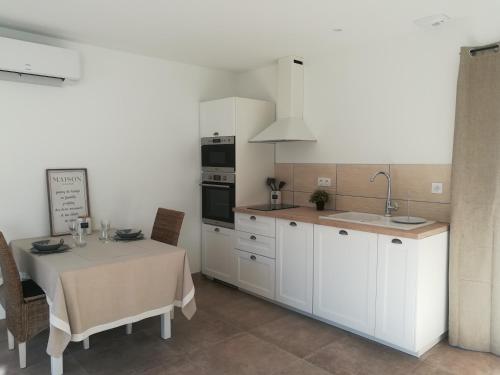 a kitchen with a table and a kitchen with white cabinets at Le Mazet d'Olivia, escapade romantique en Provence in Châteauneuf-de-Gadagne