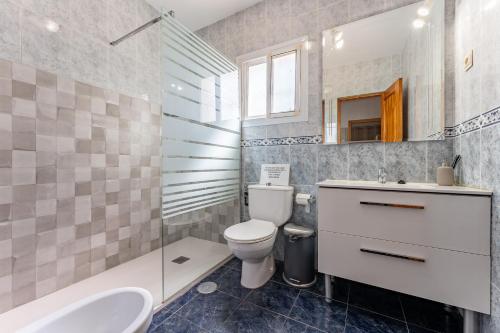 een badkamer met een toilet, een wastafel en een spiegel bij La Casa de los Recuerdos in Málaga