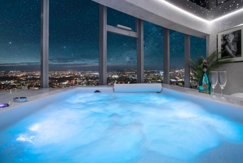 a hot tub with a view of the city at night at Apartamenty Sky Tower z Wanna Przy Oknie in Wrocław