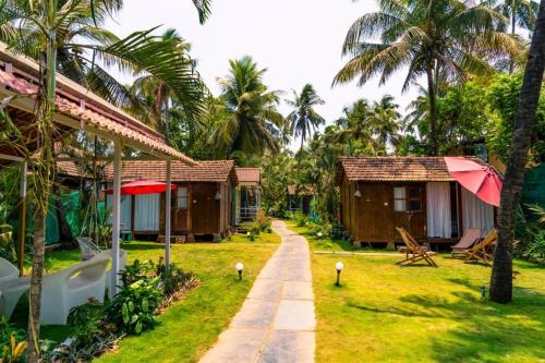 a row of cottages in a resort with palm trees at Village Susegat Beach Resort in Morjim