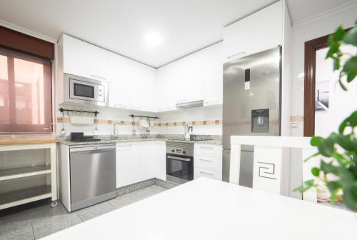 una cucina con armadi bianchi e frigorifero in acciaio inossidabile di Apartamento Las Candelas, Ares a Ares