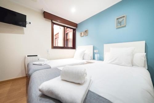 2 Betten in einem Zimmer mit blauen Wänden in der Unterkunft Apartamento Las Candelas, Ares in Ares