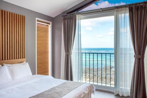 a bedroom with a large window with a view of the ocean at MJ Resort in Jeju